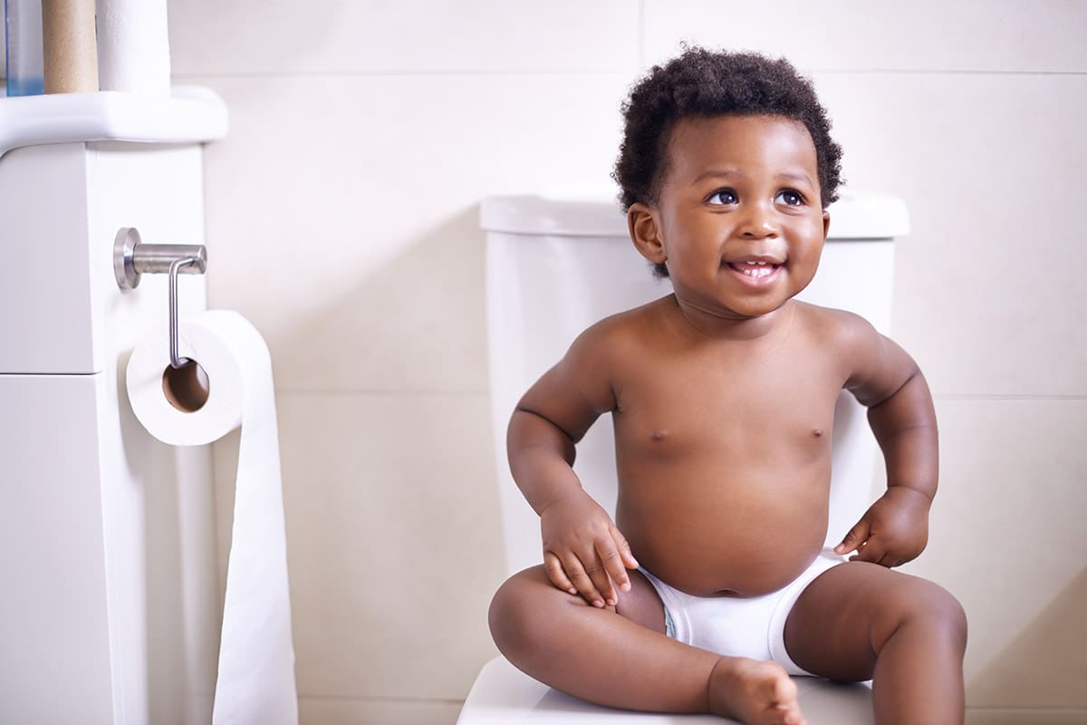 A baby sitting on top of a toilet.