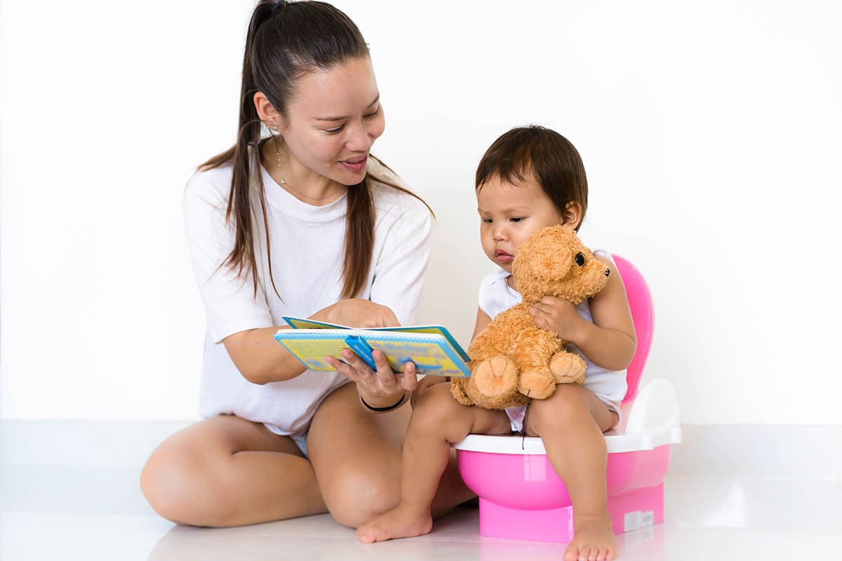 A woman sitting on the floor with a baby and reading to him.