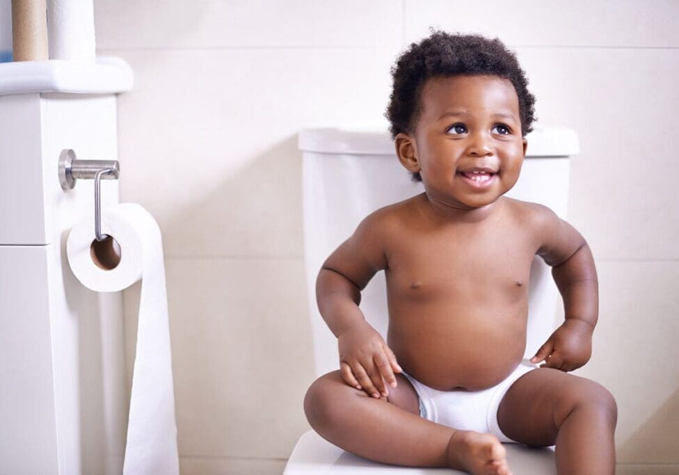 A baby sitting on top of a toilet.
